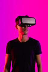 Asian man using vr headset in studio with purple light and copy space