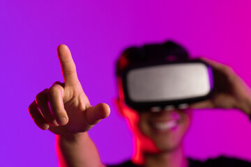 Happy asian man using vr headset in studio with purple light and copy space