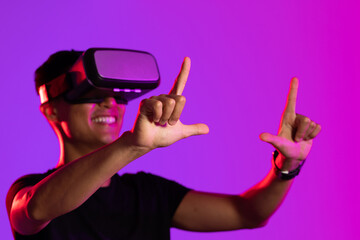 Happy asian man using vr headset in studio with purple light with copy space