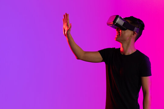 Happy asian man using vr headset in studio with purple light with copy space