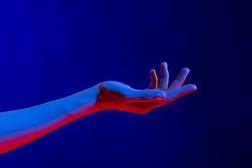 Exposed hand in studio with blue light with copy space