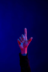 Asian man pointing finger in studio with blue light with copy space