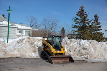 A bobcat steer loader in front of a snow bank.