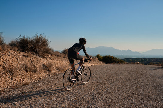 Fit male cyclist riding dirt trails on gravel bike. Man riding gravel bike on gravel road in scenic view with hills in Spain. Sport motivation.Gravel road in mountains.