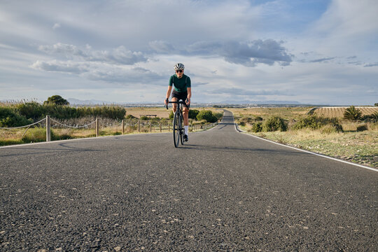 fit young female cyclist riding on the road on a gravel bike at sunset.Empty city road.
Sport motivation.Murcia region in Spain