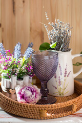 garden and country house interior on a wooden background. Lilac wine glass and jug-vase with lavender in Provence style