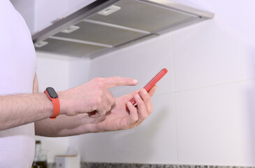 Midsection of young technician using smart phone near range hood in kitchen
