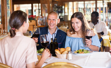 Fototapeta na wymiar Two cheerful couples having dinner and nice talking in restaurant