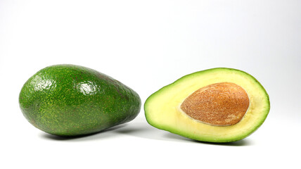 close up of a whole avocado and an avocado half on a white background