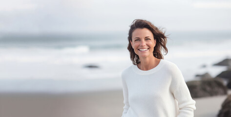 Blissful beach portrait of smiling 40-year-old brunette in light-colored clothing with soft-focus ocean backdrop. Generative AI - Powered by Adobe