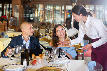 Smiling man and woman choosing evening meal in restaurant, having date