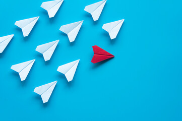 Top view red paper airplane origami leaving other white airplanes on blue background with...