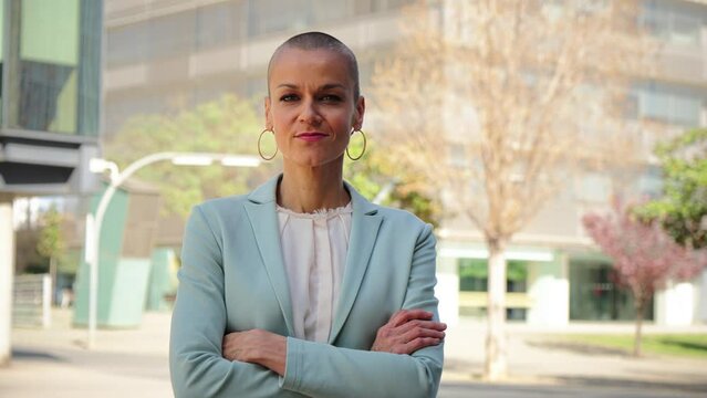 Successful business woman standing arms crossed at workplace looking at camera. Corporate female or employee folded outside of the office with proud attitude. Front view of ceo lady with blazer jacket