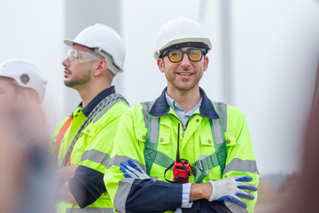 Leader of team engineer wearing safety uniform standing crosses arm looking at camera at wind turbine field renewable energy. technology protect environment reduce global warming problems.