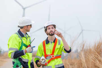 Teamwork engineer worker wearing safety uniform discuss operational planning at wind turbine field renewable energy. technology protect environment reduce global warming problems.