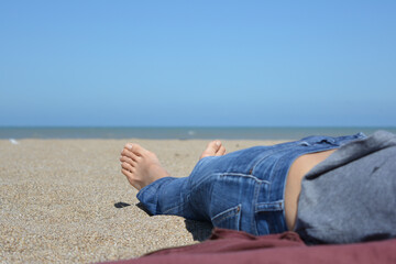 bare feet of woman lying on the beach, in the sand on vacation