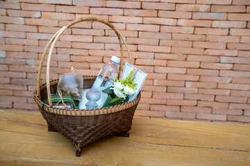 The Stuffs in a wicker basket for offer food or give alms to the monks on a wooden chair with the brick wall background.