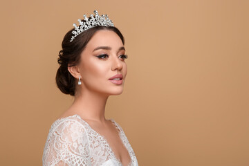 Beautiful young woman wearing luxurious tiara on beige background, space for text © New Africa