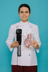 Chef holding sous vide cooker and meat in vacuum pack on light blue background