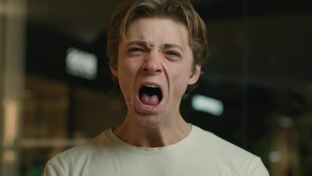 Portrait annoyed irritated emotional man aggressive yelling looking at camera shouting scream Caucasian furious angry guy mad male customer stressed client shout feel anger annoyance stress expression