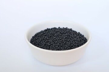 Plastic pellets for production, plastic polymer dye granules color black  on white background.