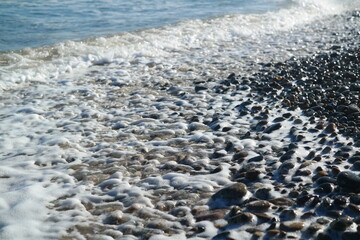 White waves crashing on a beach made of rounded pebbles