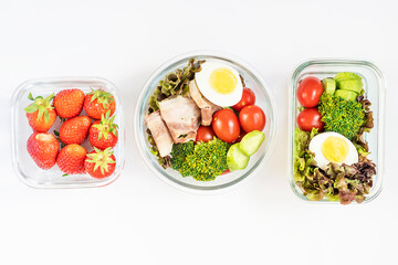 Healthy food in glass lunch boxes on white background close-up, top view.