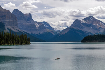 One man kayaking on Maligne Lake with a dramatic backdrop, seen from Spirit Island, Jasper national park, Canada.