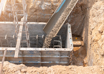 Pouring cement or concrete into foundation formwork of new building.