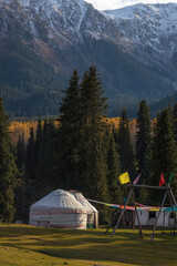 Traditional yurt house surrounded by beautiful coniferous forest and mountains in autumn, Kyrgyzstan - 589367931