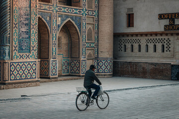 Man riding a bicycle near old madrasah in Bukhara, Uzbekistan - 589367990