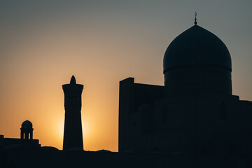 Sunrise silhouette view of minaret Kalyan and a mosque in Bukhara, Uzbekistan - 589367993