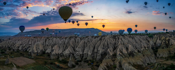 Sunrise panorama of famous Cappadocia landscape view with lots of hot air balloons flying - 589367997