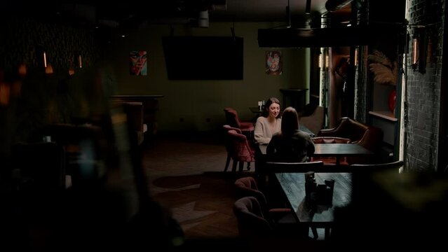 two young girlfriends sit relaxed in a hookah bar and cheerfully discuss something the concept of recreation