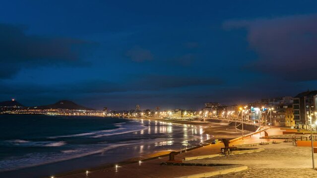 Timelapse of the island of las palmas de gran canarias, spain, view of the beach la cícer and playa de las canteras with movement of clouds and tourists walking along the waterfront, from day to night