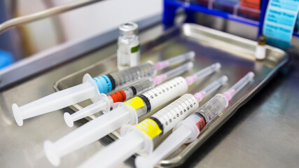 A medical syringe with a colorful tag label on stainless tray in hospital.Drug preparation for...