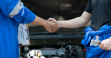 Car mechanic, professional technician shake hands in car repair success engine care Check the...