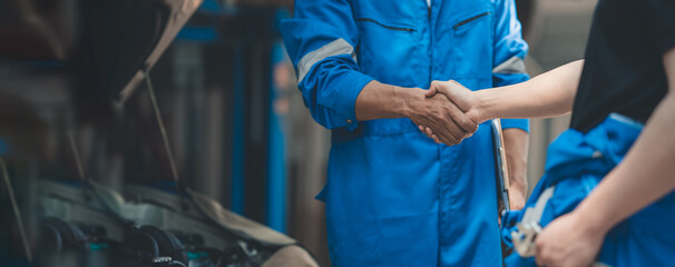 Car mechanic, professional technician shake hands in car repair success engine care Check the...