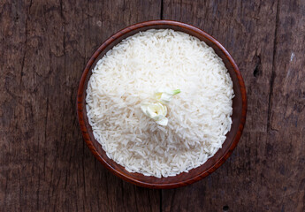 white rice (Jasmine rice) served in a wooden bowl, isolated over wooden background