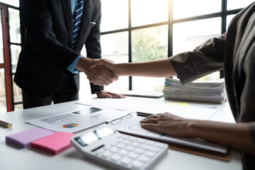 Two confident businessmen shaking hands during meeting in office and mutual investment in financial business that fits and succeeds in office.