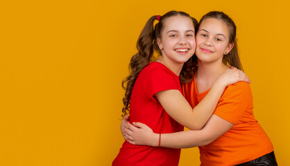 happy children embracing on yellow background. sisterhood