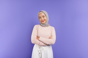 portrait of an Asian Muslim woman posing, smiling, and looking at the camera, isolated on a purple...