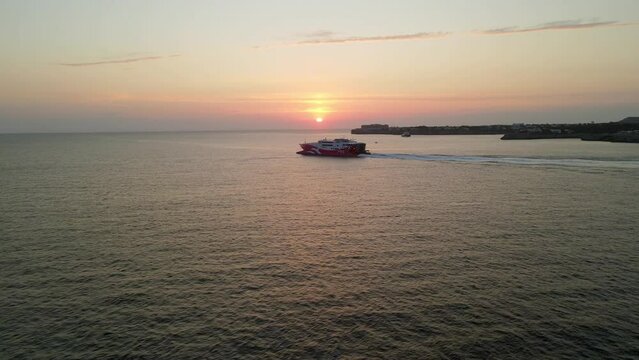 Sunset in the background as cargo ship leaves the port in Spain to cross the Mediterranean Sea.