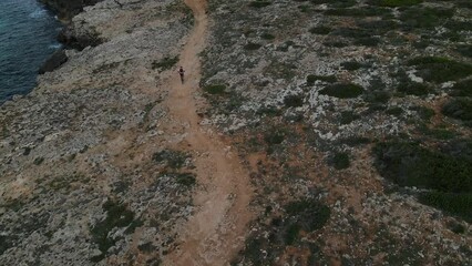 Coastal mountain bike event along the shoreline of Menorca Spain. The last riders are seen completing the path as the sun sets.