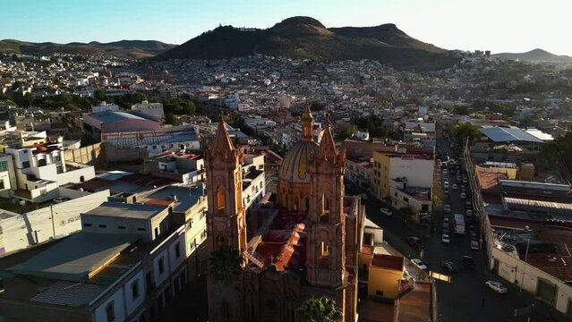 Aerial view passing the Cathedral of Zacatecas, overlooking the city, golden hour in Mexico