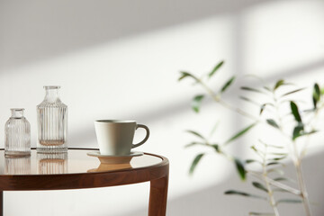 This room has a calm atmosphere with natural light. There are clay pots, glass bottles, coffee and various objects on the table.
