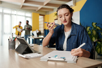 Businesswoman listening to voice message from colleague when checking report