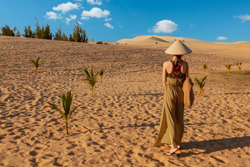 Lonely woman in sand dunes rear view.