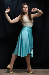 Naklejka premium Dancing woman in a blue skirt posing against a black background. Full length portrait