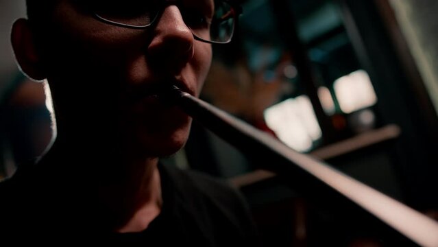 A hookah man in glasses smokes a traditional hookah pipe A man exhales smoke in a hookah cafe or lounge bar close-up